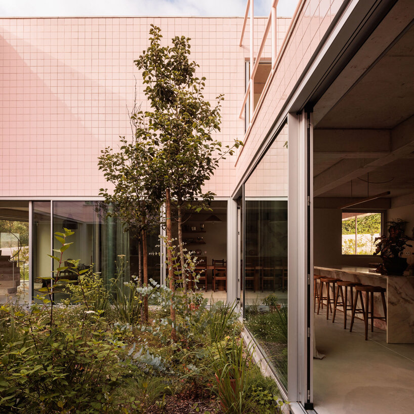 atelier RUA's light pink house contrasts with surrounding greenery in portugal