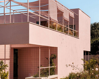 atelier RUA's light pink house contrasts with surrounding greenery in portugal