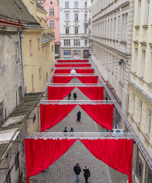 red and white curtains transform czech historic center’s pathways into christmas installation