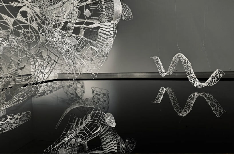 crocheted zodiac animal installations by choi+shine suspend above dark body of water