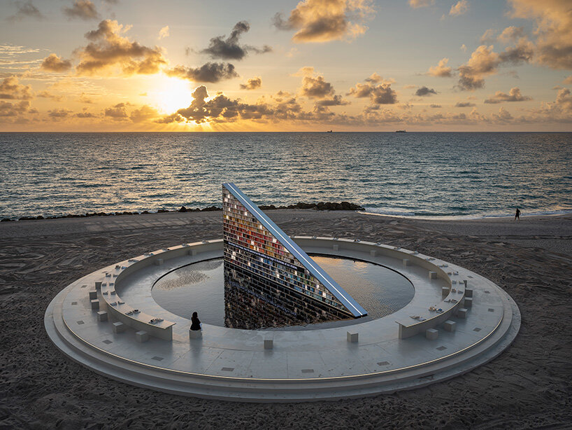 estantería triangular diseñada por es devlin para la semana del arte de miami 2025 gira dentro de una piscina con espejos