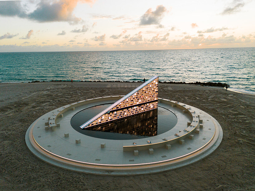 estantería triangular diseñada por es devlin para la semana del arte de miami 2025 gira dentro de una piscina con espejos