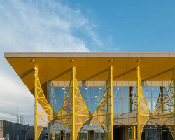 semi-transparent yellow metal arches frame airport’s terminal extension in romania