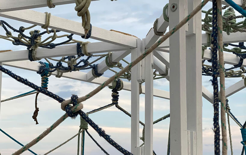 triangular wooden pavilion floats on reused plastic gallons along croatia’s coasts