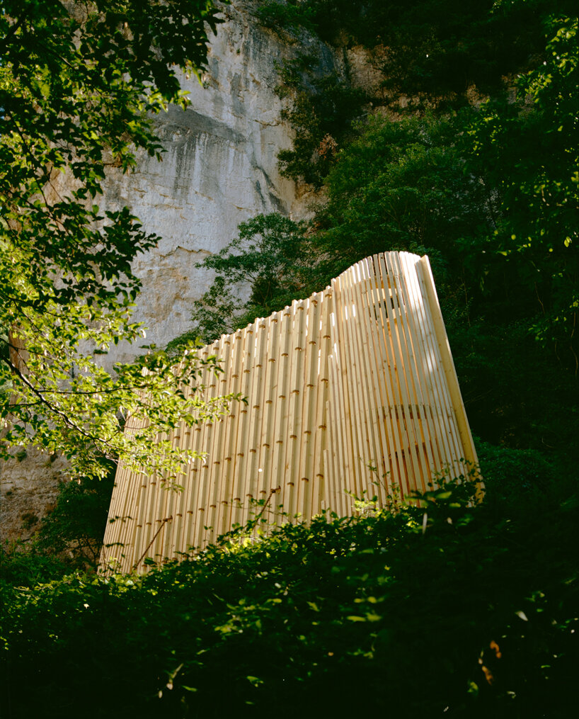 river chapel pavilion lands as an overturned timber vessel in the italian mountains