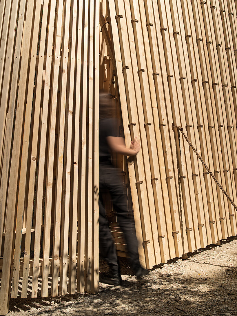 river chapel pavilion lands as an overturned timber vessel in the italian mountains