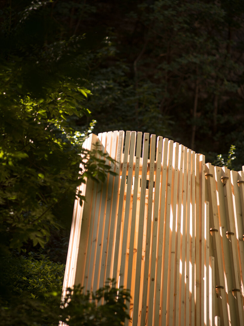 river chapel pavilion lands as an overturned timber vessel in the italian mountains