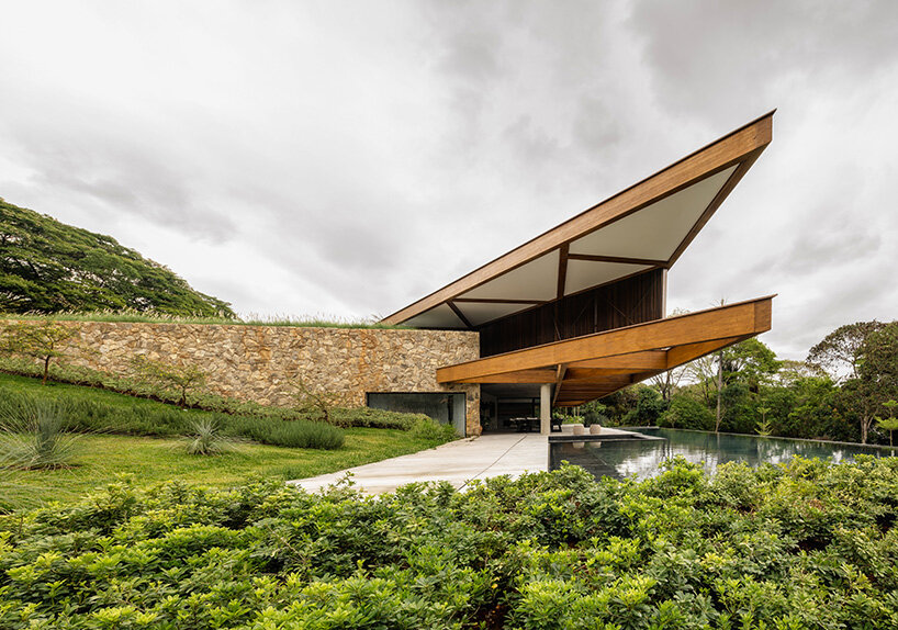 La casa de TETRO junto al lago en Brasil desaparece en el horizonte bajo techos triangulares de madera