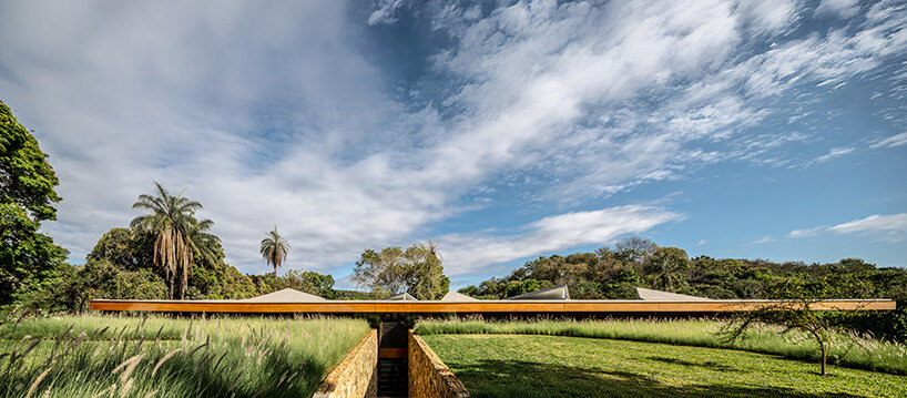 La casa de TETRO junto al lago en Brasil desaparece en el horizonte bajo techos triangulares de madera