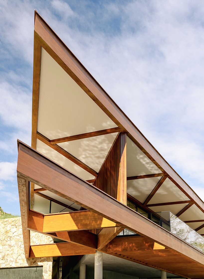 La casa de TETRO junto al lago en Brasil desaparece en el horizonte bajo techos triangulares de madera