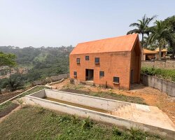clay monolithic villas emerge from ghana’s red earth landscape
