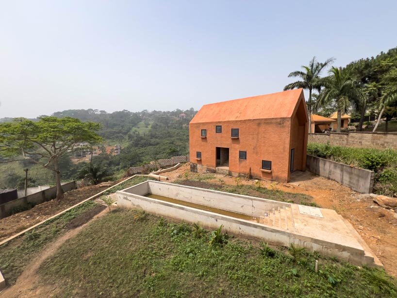 clay-pigmented monolithic villas emerge from ghana&rsquo;s red earth landscape