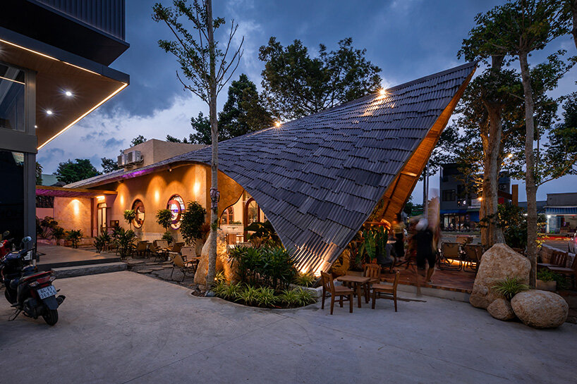 rippling metal roof drapes over interlocking stone volumes of vietnamese caf&eacute;