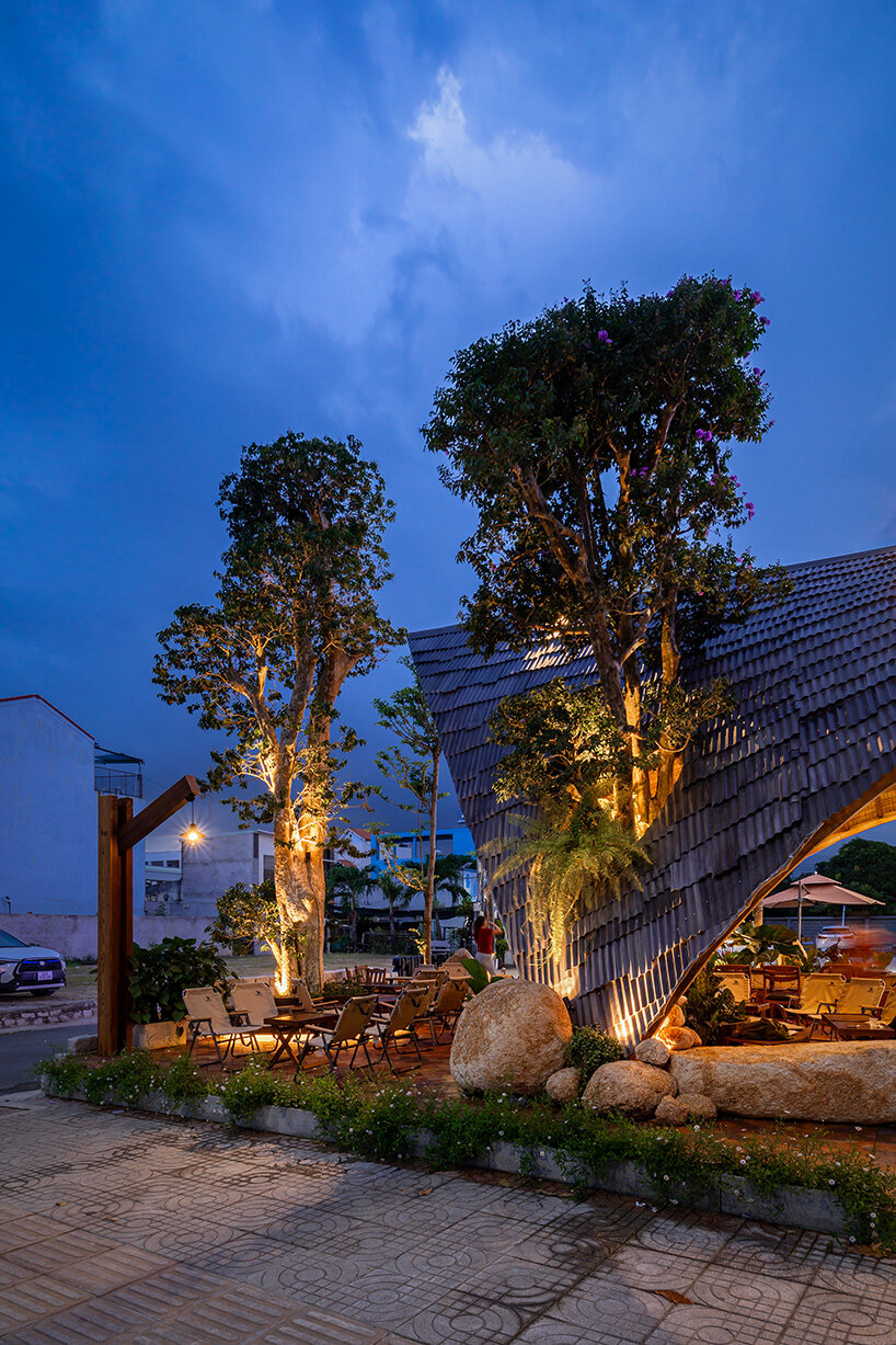 rippling metal roof drapes over interlocking stone volumes of vietnamese caf&eacute;