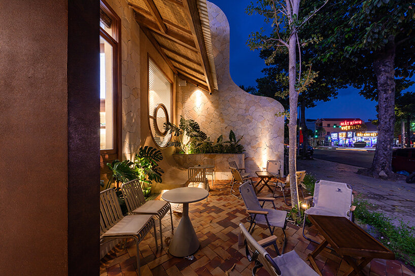 rippling metal roof drapes over interlocking stone volumes of vietnamese caf&eacute;