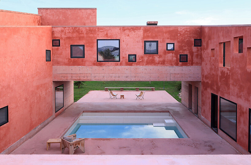 square openings punctuate the facade of courtyard-centric red house in albania