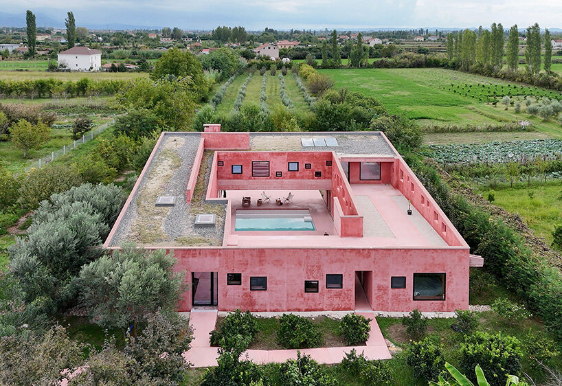 square openings punctuate the facade of courtyard-centric red house in albania