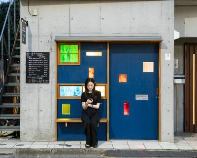 colored glass apertures reveal lively tokyo bar through bright blue entrance