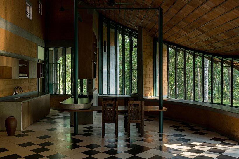 a semi-circular porous brick house stands amid rubber plantation in india