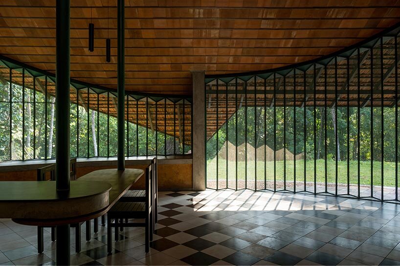 a semi-circular porous brick house stands amid rubber plantation in india