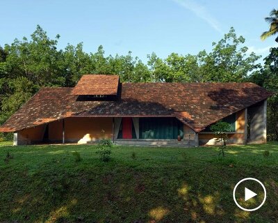a semi-circular porous brick house stands amid rubber plantation in india