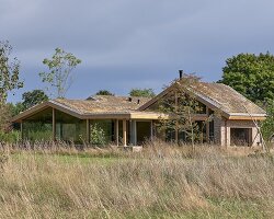 single draped roof unites brick, wood, and glass for teamtonbo house in the netherlands