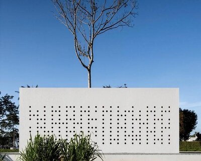 white perforated cubic facade wraps hybrid home and studio around a tree in brazil