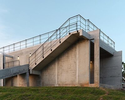 repetitive vertical fins enfold concrete structure embedded within thailand’s mountainscape