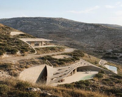 warm-toned concrete forms and planted roofs blend into the cycladic landscape of kythnos