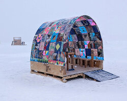a quilt-wrapped ice shanty brings patchwork colors to a frozen minnesota lake
