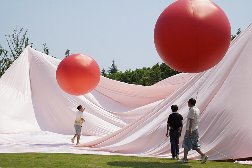 red balloons lift flowing fabric into a wedding playground by suki+partners in china - 1