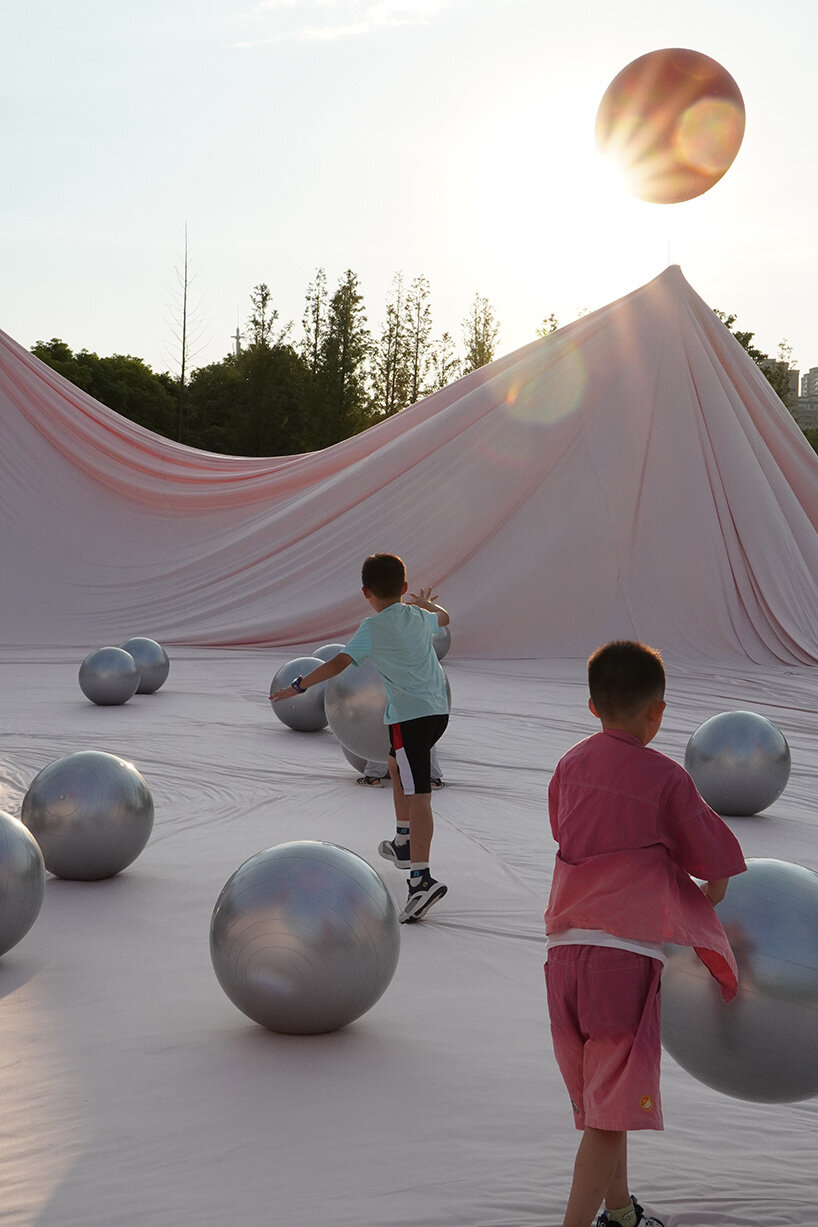 red balloons lift flowing fabric into a wedding playground by suki+partners in china - 10