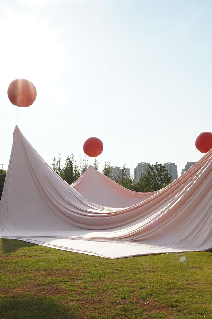 red balloons lift flowing fabric into a wedding playground by suki+partners in china - 8