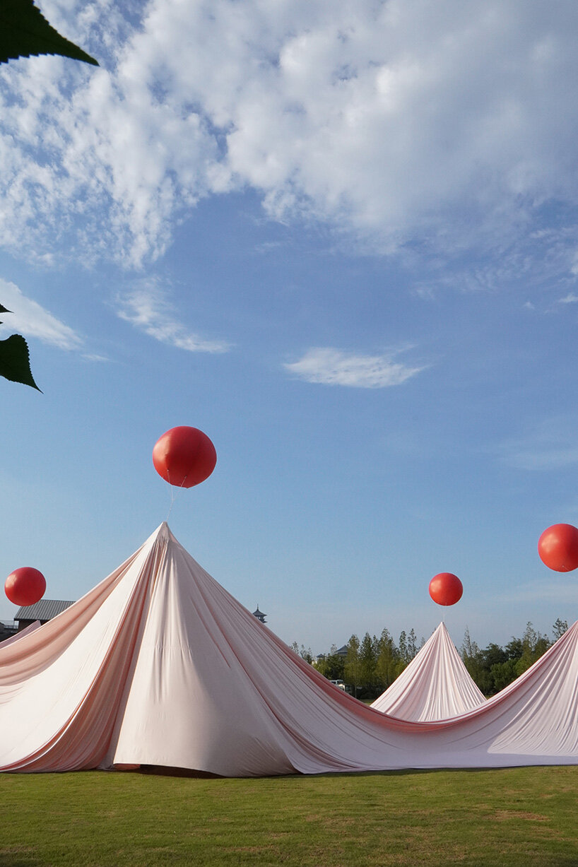 red balloons lift flowing fabric into a wedding playground by suki+partners in china - 2