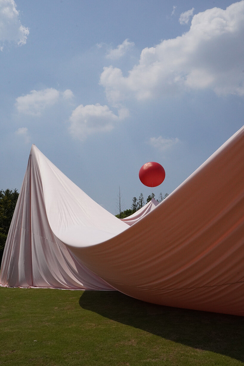 red balloons lift flowing fabric into a wedding playground by suki+partners in china - 9