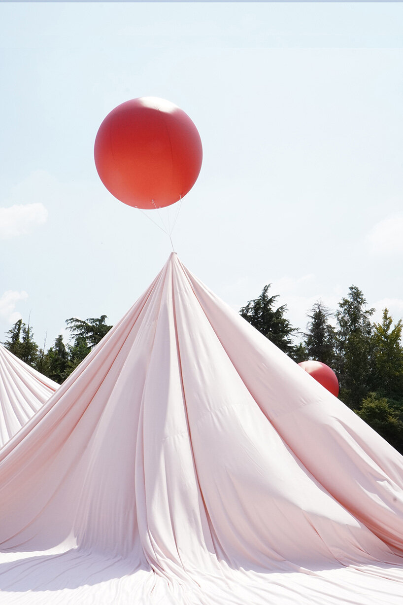 red balloons lift flowing fabric into a wedding playground by suki+partners in china - 7