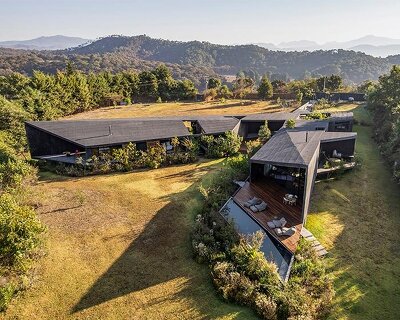 two intersecting volumes of black concrete carve mavra house into the mexican landscape