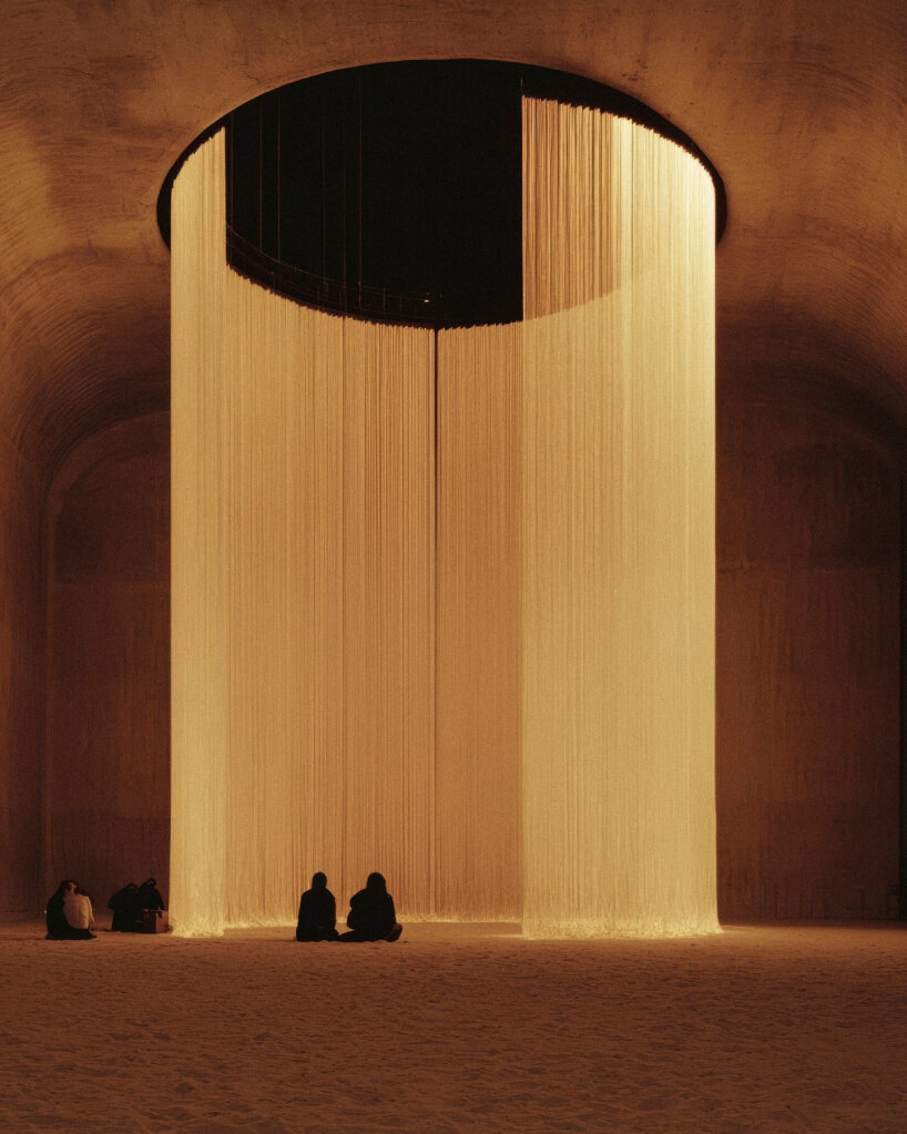 a cylindrical column of vertical threads or fine cords drops from a circular aperture in a vaulted ceiling