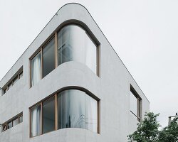 curved concrete volumes interlock through glass hinge to extend oom house in bangkok