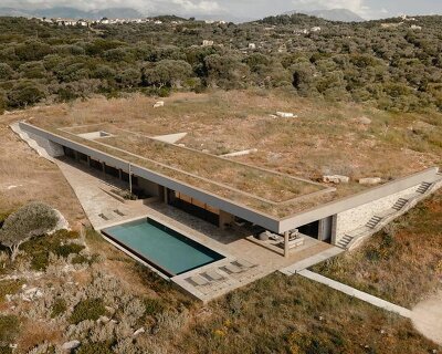 linear stone residence emerges within greek island’s untouched coastal terrain