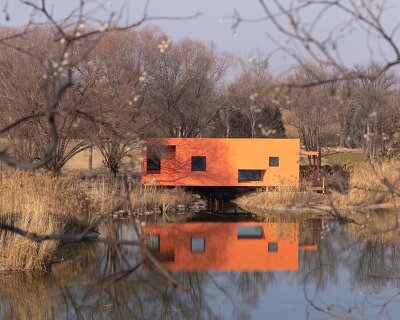 playful crimson timber cabin floats above a stream in chinese cultural park
