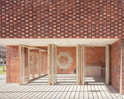 glazed facade cuts through monolithic brick community center within paris park