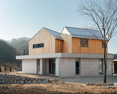 this home in korea is shaped by twin timber gables atop a concrete base