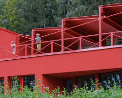 red steel sawtooth roofs emerge through spruce forest in czech republic