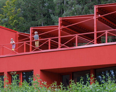 red steel sawtooth roofs emerge through spruce forest in czech republic