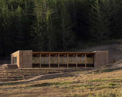 earth-toned concrete bike refuge emerges from ecuador’s reforested landscape