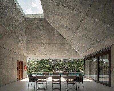 a pair of banyan trees anchors anonym studio’s open-air family house in thailand