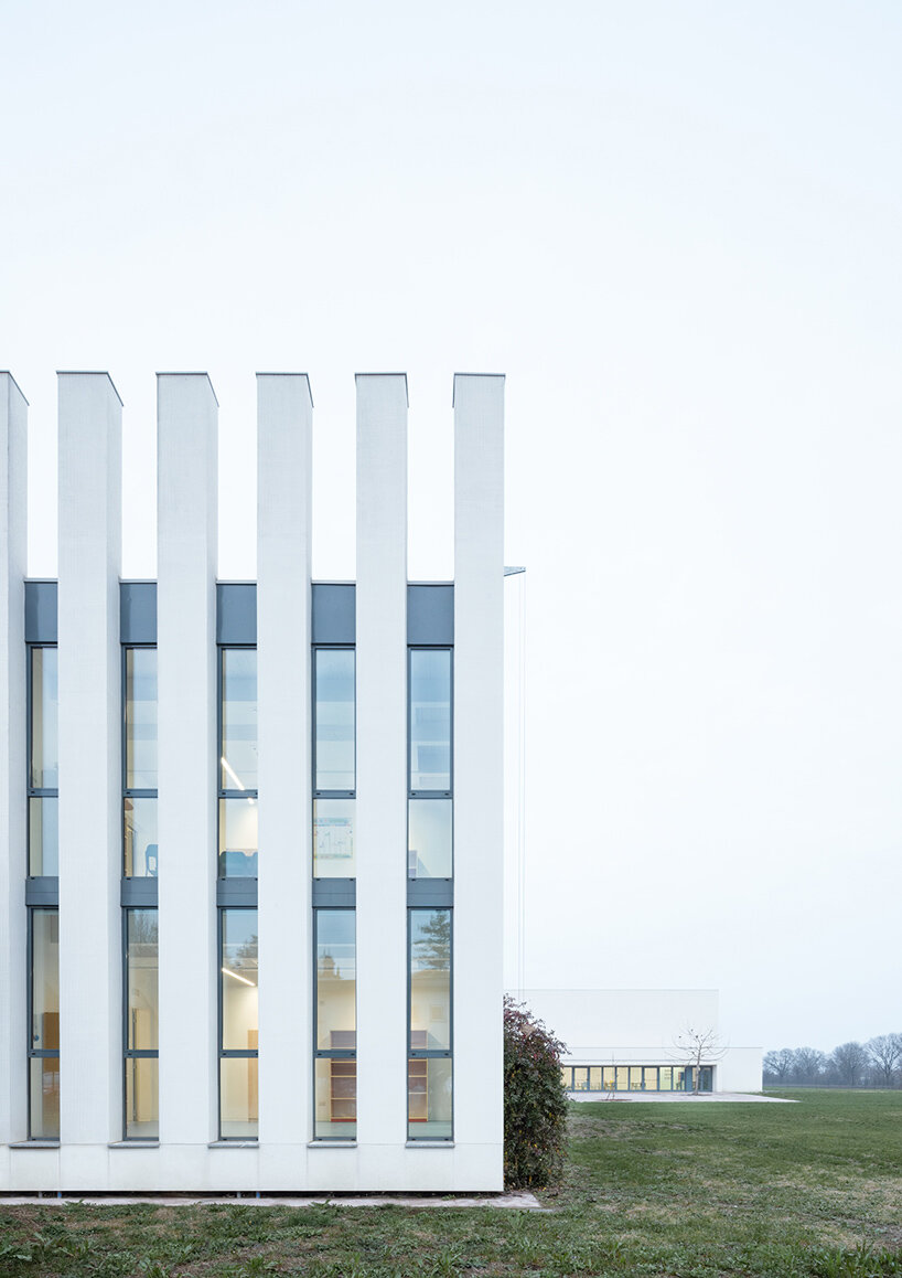 vertical white pillars compose rhythmic facade enfolding primary school in italy - 4