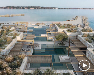 beach club’s stepped stone volumes and timber pergolas surround lagoon-like pool in greece