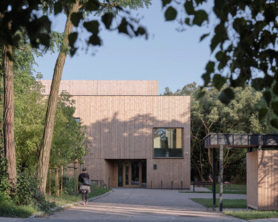 public library clad in washed timber integrates with warsaw's wooded neighborhood